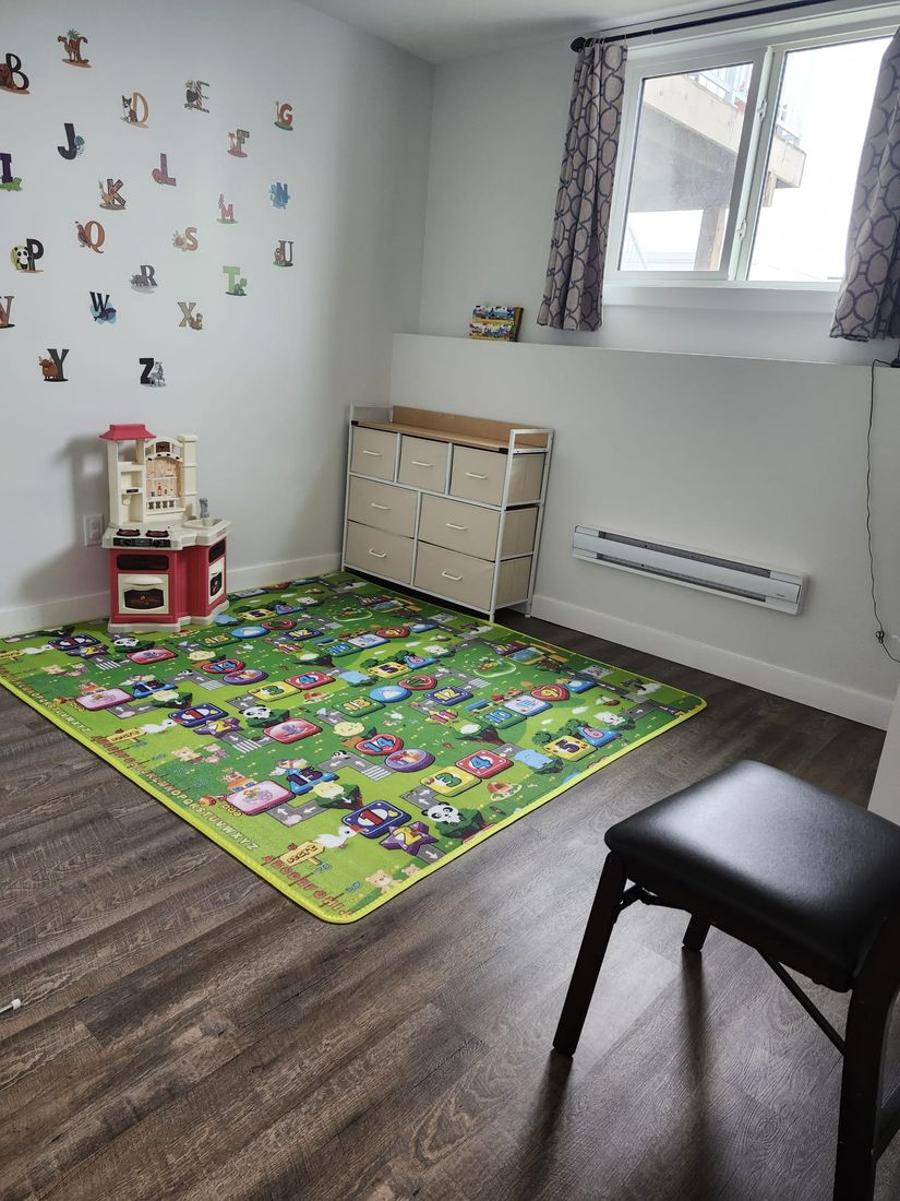 Bright indoor play room with an alphabet rug and toys