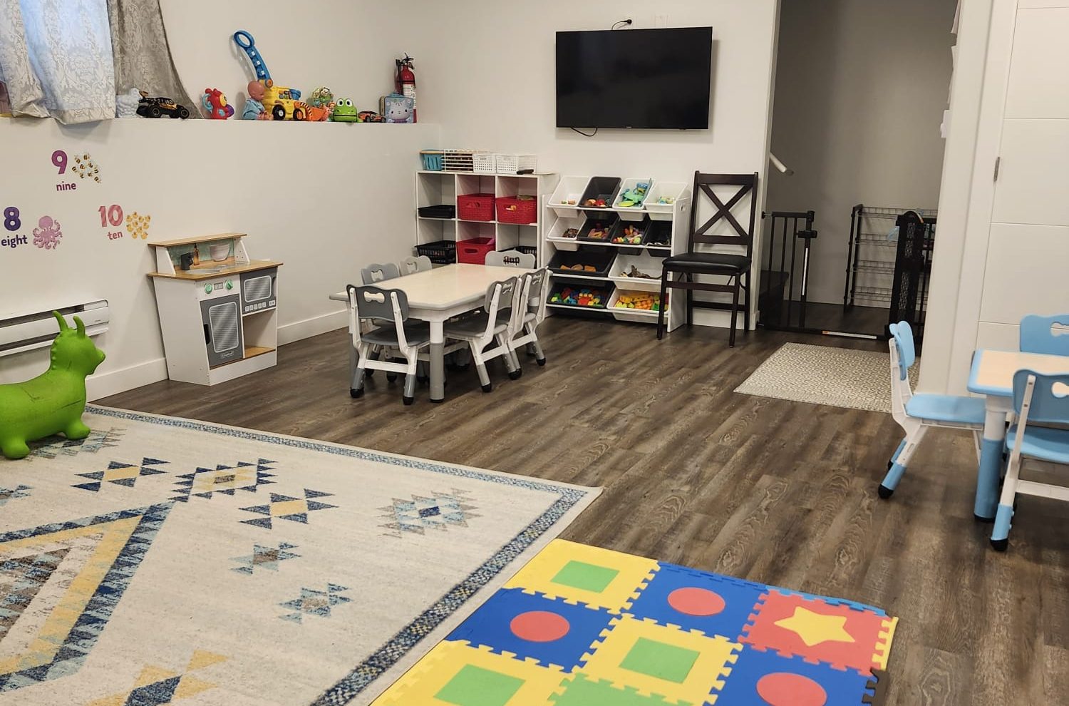 Bright indoor playroom at Mini Castle Daycare with toys, tables, and a colorful play mat